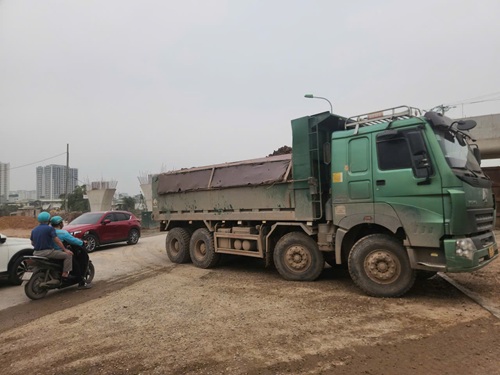 Xe tải lớn chở đất không che chắn rơi vãi bùn đất ra đường. Ảnh: Minh Hạnh
