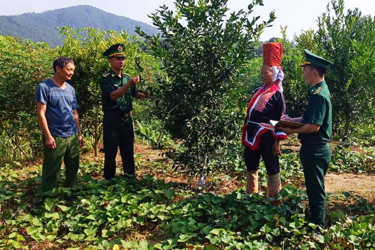 Cán bộ chiến sĩ Đồn Biên phòng Cửa khẩu Hoành Mô giúp người dân thôn Nà Choòng xây dựng vườn mẫu. Ảnh: Mỹ Dung