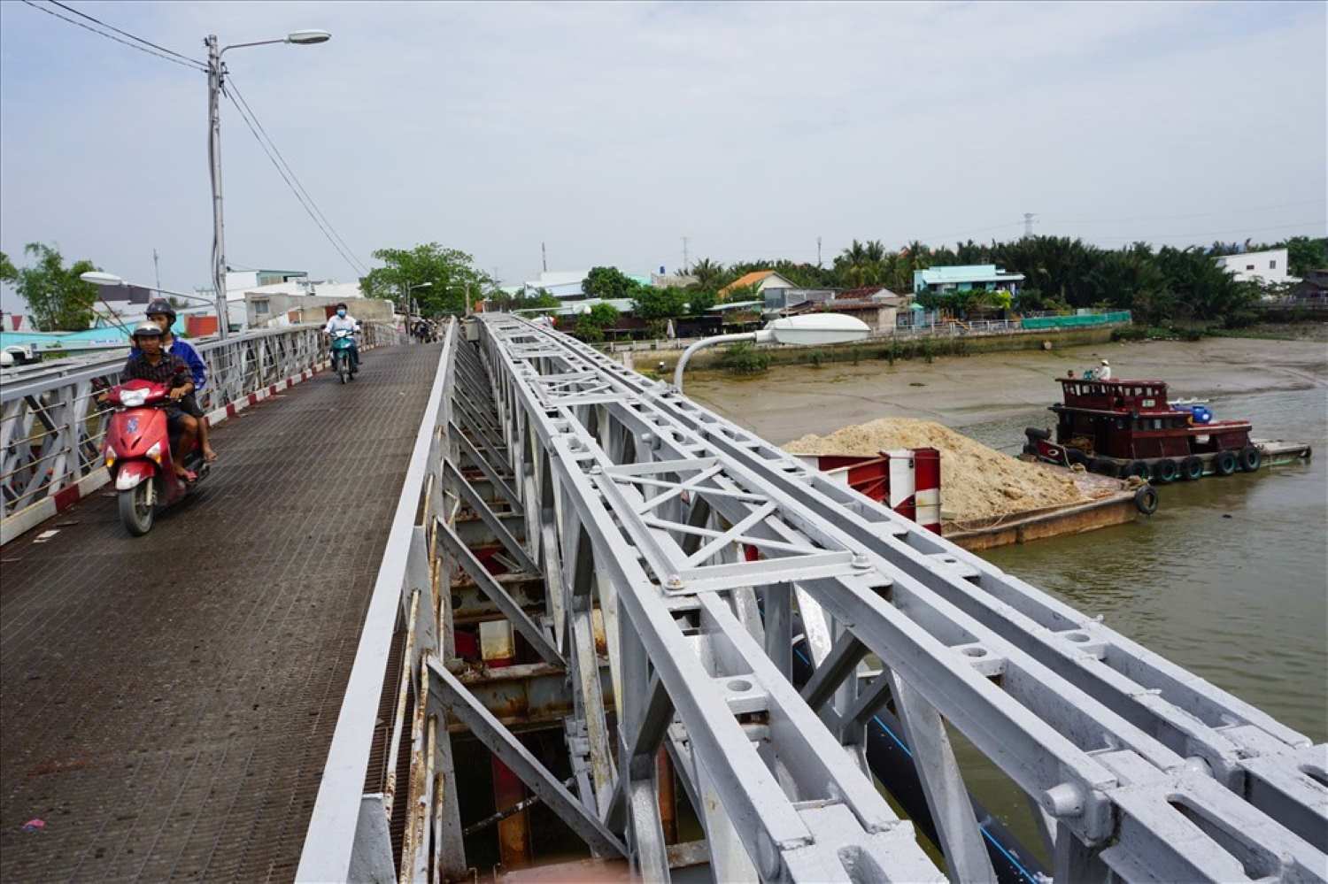 Một chiếc sà lan chở đầy cát luồn lách chui qua cầu Rạch Dơi. Ảnh: Minh Quân