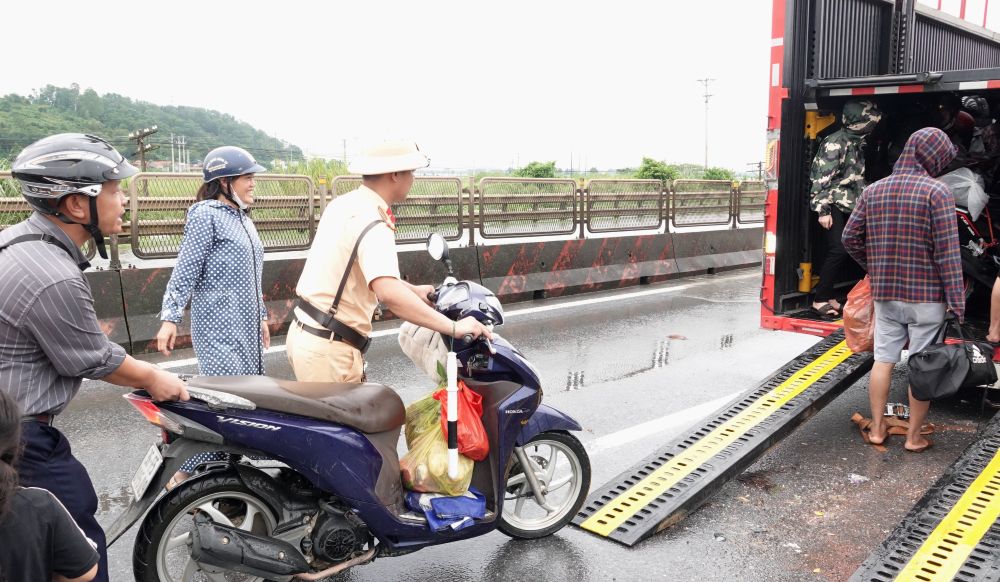 CSGT Thanh Hóa hỗ trợ, đẩy xe máy lên thùng ô tô để đi qua đoạn đường ngập. Ảnh: Quách Du