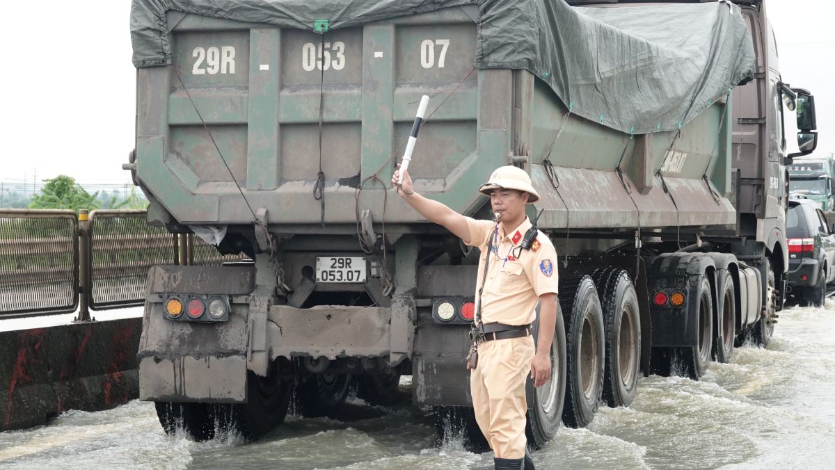 Lực lượng CSGT điều tiết, phân luồng các phương tiện qua đoạn đường bị ngập. Ảnh: Quách Du