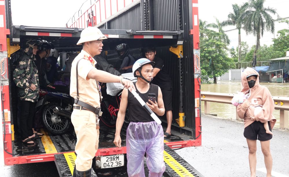 Trước tình trạng trên, chiến sĩ CSGT Thanh Hóa đã phải đề nghị xe tải (loại xe chuyên dụng chở ô tô) hỗ trợ, giúp xe máy qua đoạn đường ngập. Ảnh: Quách Du