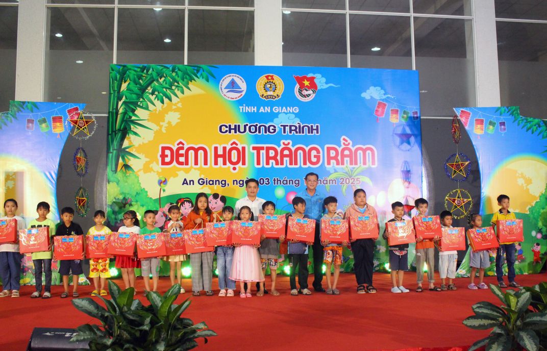 Ông Nguyễn Hữu Ngọc - Phó Trưởng Ban Tuyên giáo Dân vận và Tỉnh ủy và ông Nguyễn Nhật Tiến phát quà cho các cháu thiếu nhi trên sân khấu. Ảnh: Thanh Mai