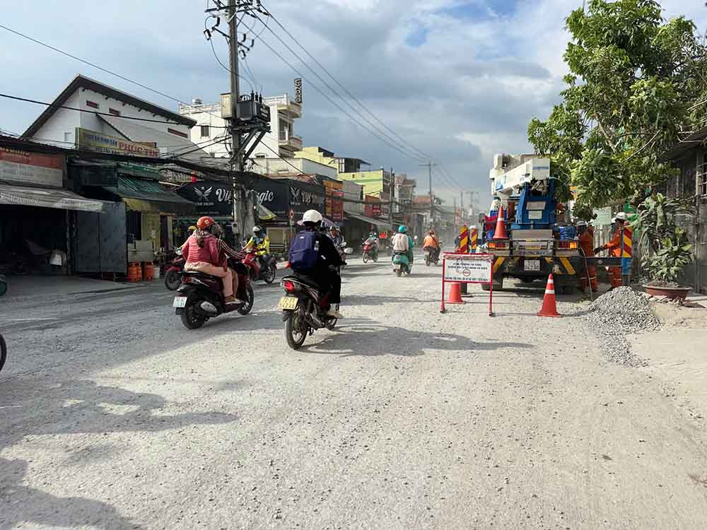 Nhiều phương tiện lưu thông khiến bụi từ mặt đường Quốc lộ 50 bay mù mịt, ảnh hưởng đến khu dân cư hai bên đường. Ảnh: Thanh Vũ
