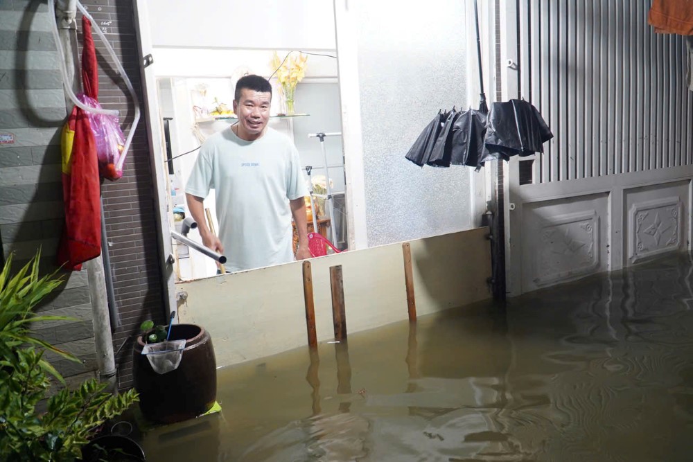 Anh Hoàng Văn Khoa cùng gia đình kê đồ đạc, dùng máy bơm để chống ngập trong triều cường tối 24.10.