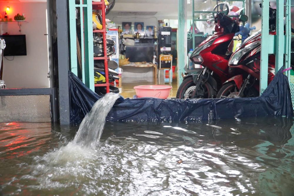 Máy bơm mini được đặt ngay trước cửa nhà, hoạt động hết công suất để bơm hút nước ra khỏi nhà. Ảnh: Thái Bảo