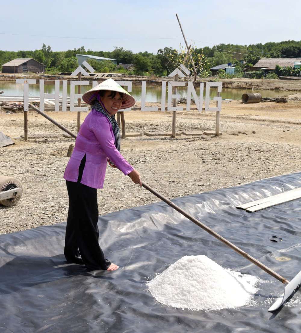 Du khách hào hứng xắn quần lội ruộng, tự tay cầm cào thu hoạch để thấu hiểu hơn về sự vất vả và giá trị của hạt muối Thiềng Liềng. Ảnh: Thái Bảo