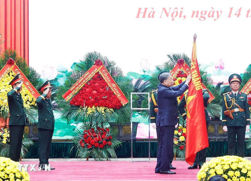Tổng Bí thư Tô Lâm gắn Danh hiệu Anh hùng Lực lượng vũ trang nhân dân lên Quân kỳ Quyết thắng của Tổng cục Hậu cần - Kỹ thuật. Ảnh: TTXVN
