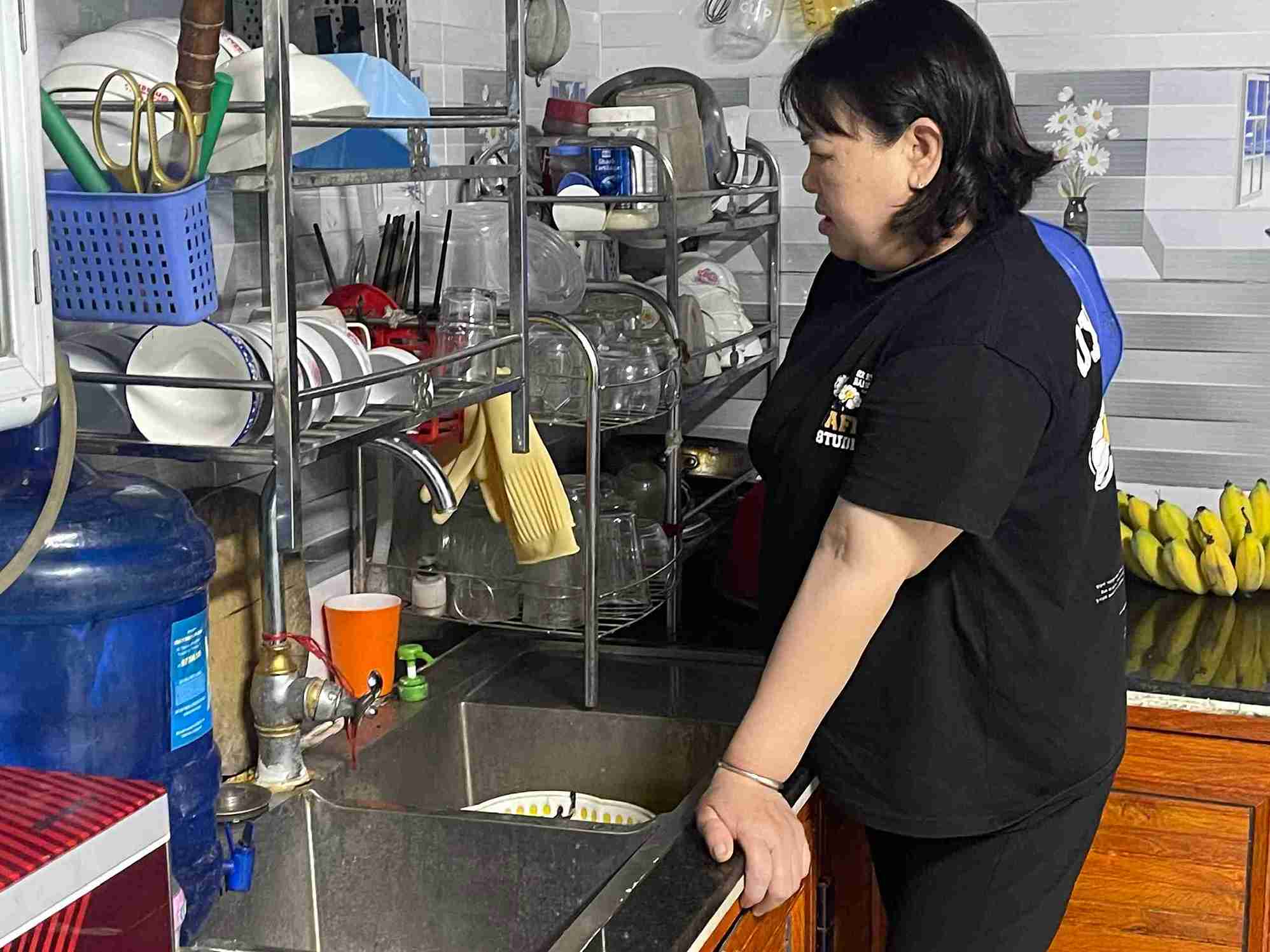 Bà Nguyễn Thị Tính đứng bên bồn rửa bát, thở dài vì tình trạng thiếu nước kéo dài.