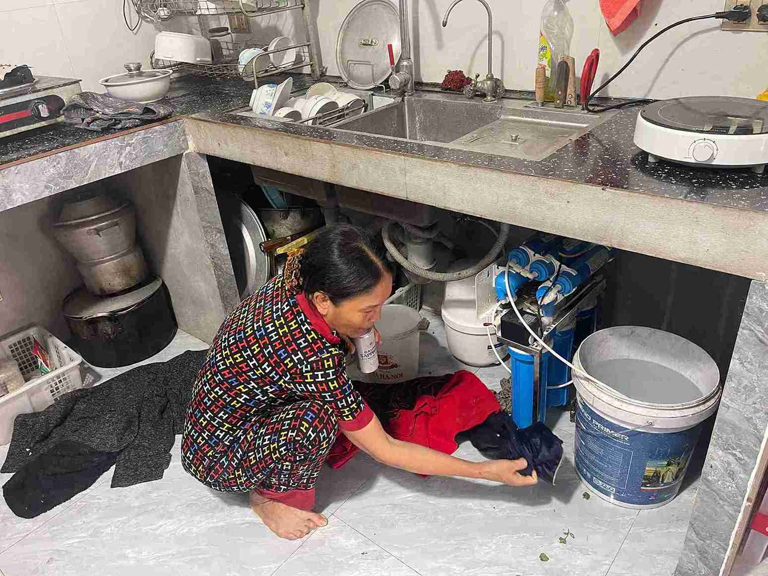 Bà Chuyển kiểm tra máy lọc nước, lõi mới thay nhưng vẫn bám cặn bẩn.