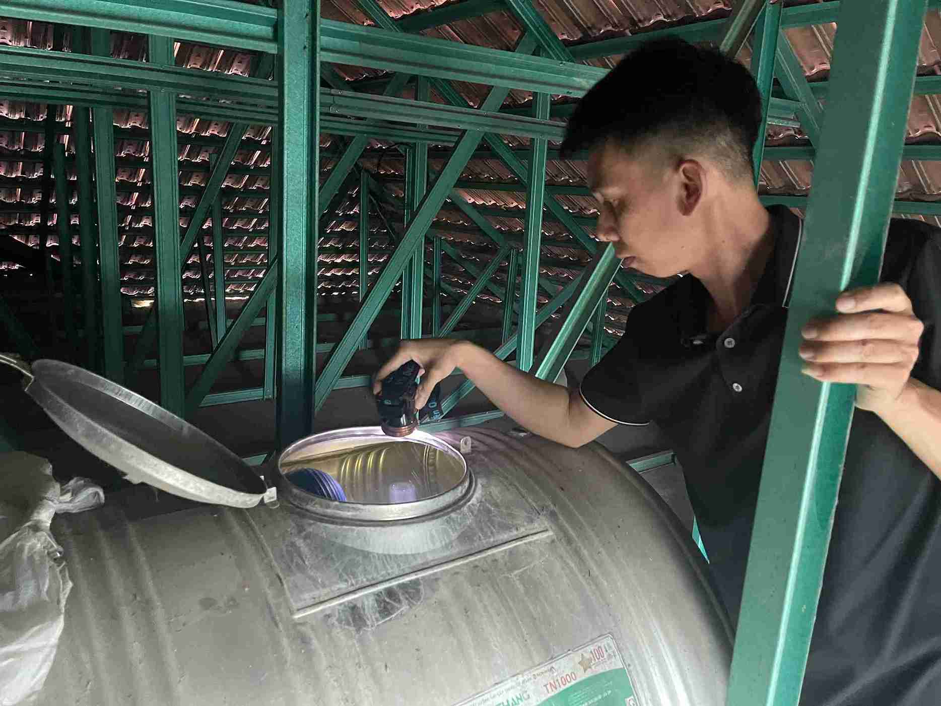 Anh Bùi Quang Nghiêm kiểm tra téc nước trên mái nhà, ghi nhận nước đục và có cặn bẩn.