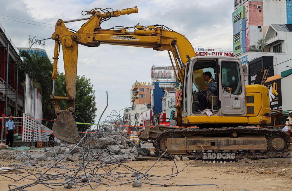 Máy đào được huy động phá dỡ các hạng mục cũ trên tuyến đường đông phương tiện qua lại. Công trường phải vừa thi công, vừa bảo đảm giao thông và hạn chế ảnh hưởng đến hoạt động kinh doanh của người dân.