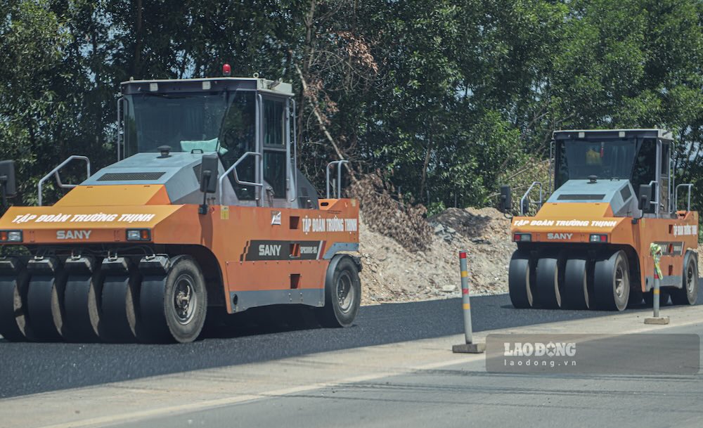 Máy đào, xe tải và thiết bị chuyên dụng được huy động tại các vị trí mở rộng nền đường. Trên công trường, nhiều hạng mục được triển khai đồng thời nhằm bù đắp tiến độ trong điều kiện thời tiết nắng nóng.