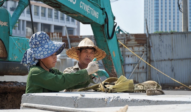 Một số công nhân luồn dây nâng qua cống bê tông, chuẩn bị cho công tác di chuyển cống tại công trường.